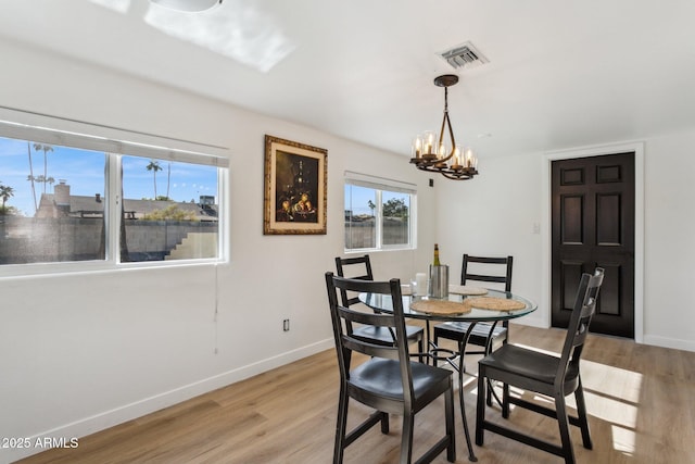 dining space with light wood-type flooring and an inviting chandelier