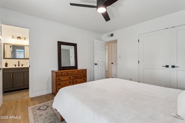 bedroom featuring connected bathroom, sink, a closet, light wood-type flooring, and ceiling fan