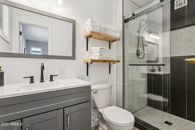 bathroom featuring toilet, an enclosed shower, and vanity