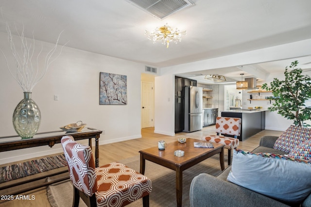 living room featuring a chandelier, light hardwood / wood-style flooring, and beam ceiling