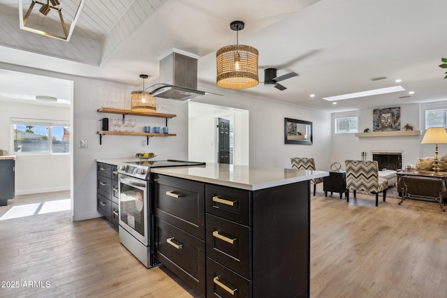 kitchen featuring island exhaust hood, light hardwood / wood-style floors, hanging light fixtures, stainless steel electric range oven, and ceiling fan