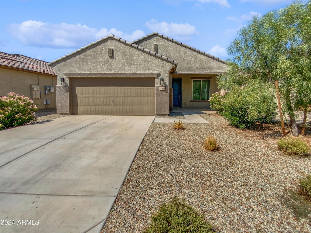 view of front of property featuring concrete driveway, an attached garage, a tile roof, and stucco siding