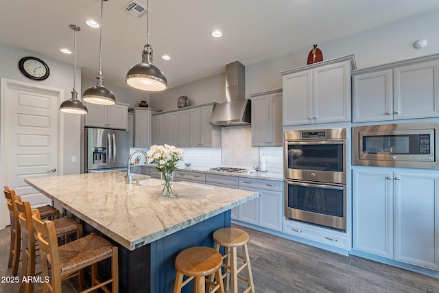10207 W Hedge Hog Pl, Peoria, AZ 85383 - kitchen featuring stainless steel appliances, wall chimney range hood, a kitchen breakfast bar, backsplash, and light stone countertops