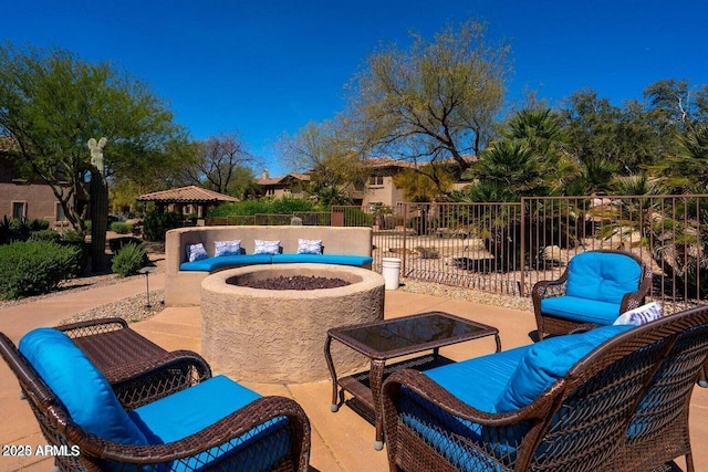 view of patio with an outdoor living space with a fire pit and fence