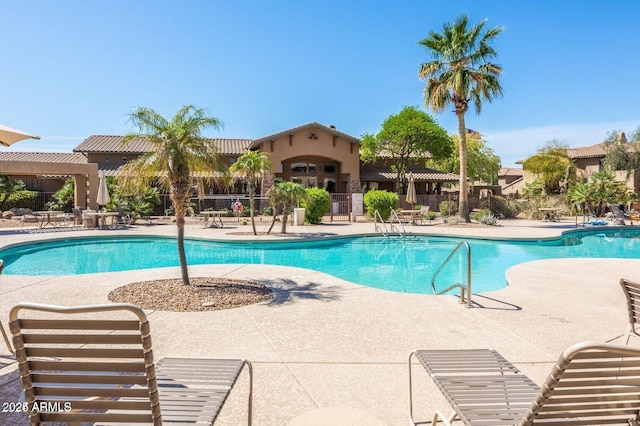 community pool with a patio area and fence