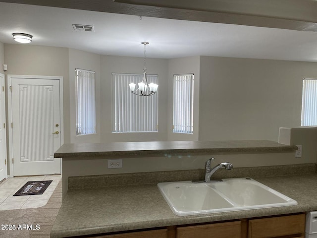 kitchen with visible vents, a chandelier, pendant lighting, light tile patterned flooring, and a sink