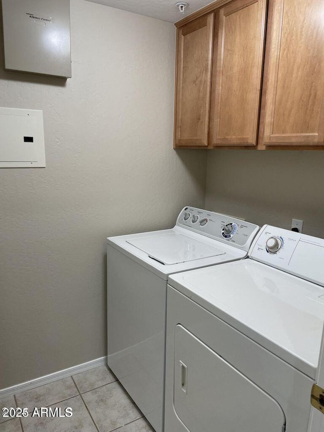 laundry area with light tile patterned floors, baseboards, cabinet space, and separate washer and dryer