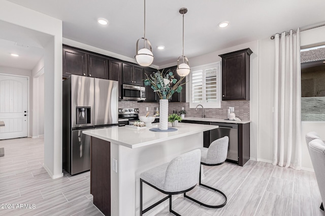 kitchen featuring pendant lighting, sink, dark brown cabinets, stainless steel appliances, and a center island