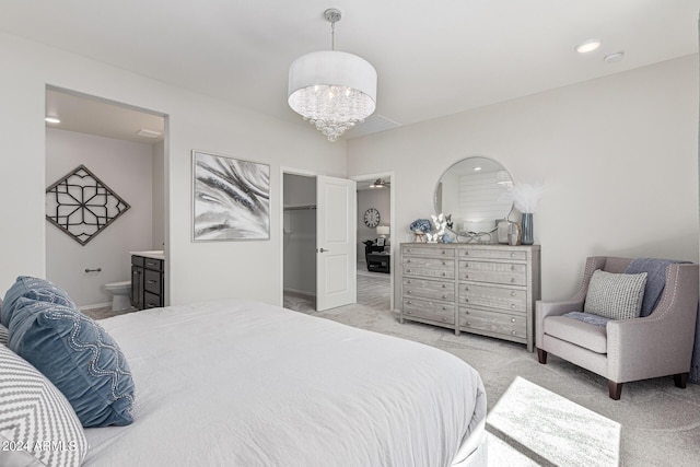 carpeted bedroom featuring connected bathroom, a spacious closet, and a chandelier