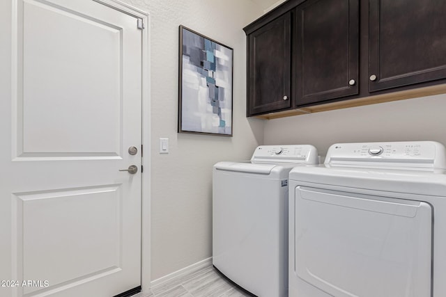 clothes washing area with washer and clothes dryer and cabinets