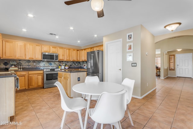 kitchen with light brown cabinets, appliances with stainless steel finishes, decorative backsplash, and light tile patterned floors