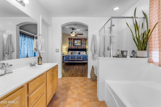 bathroom with tile patterned flooring, vanity, ceiling fan, and plus walk in shower