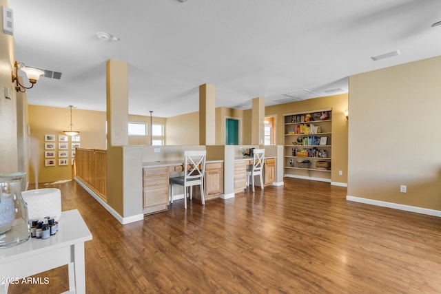 kitchen featuring light brown cabinetry, dark hardwood / wood-style floors, kitchen peninsula, built in features, and pendant lighting