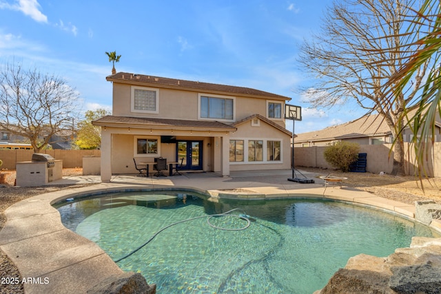 back of house featuring exterior kitchen, a fenced in pool, and a patio area