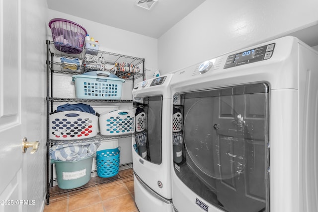 laundry room with washer and dryer and light tile patterned flooring