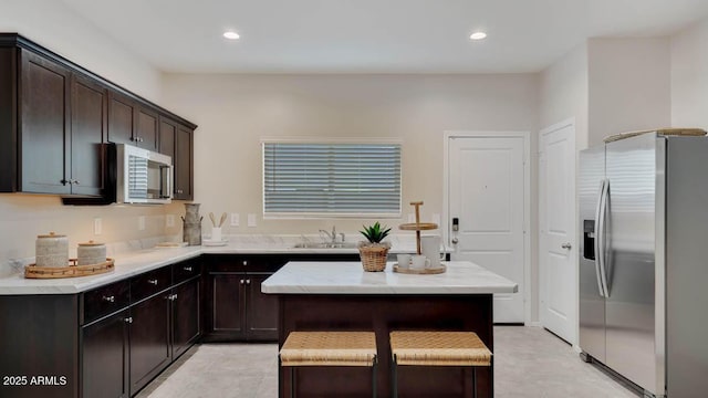24052 W Pima St, Buckeye, AZ 85326 - kitchen featuring appliances with stainless steel finishes, dark brown cabinetry, recessed lighting, a kitchen island, and light stone countertops