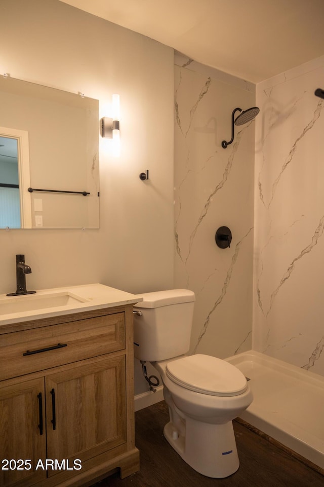 bathroom with wood-type flooring, toilet, walk in shower, and vanity