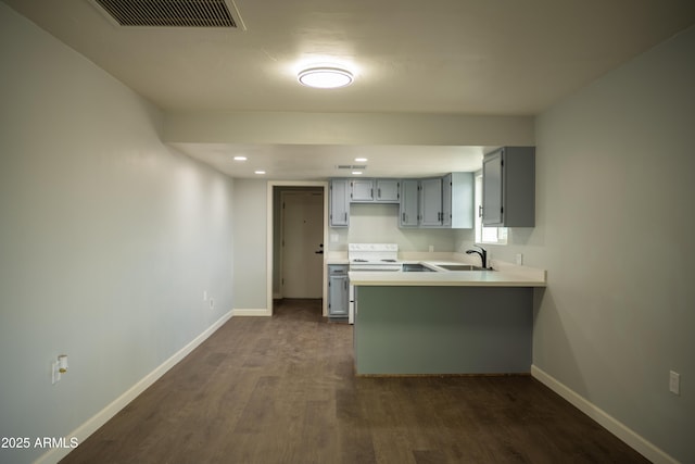 kitchen featuring kitchen peninsula, dark hardwood / wood-style flooring, sink, gray cabinets, and range