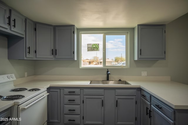 kitchen with white electric range, gray cabinetry, and sink