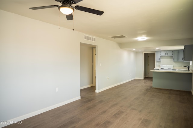 unfurnished living room with ceiling fan, sink, and dark hardwood / wood-style flooring