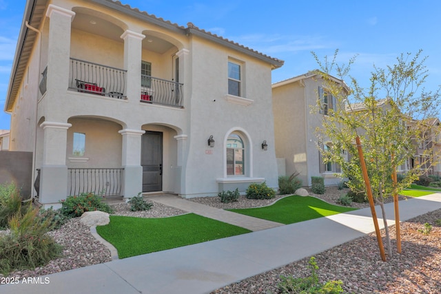 mediterranean / spanish house featuring a porch, a balcony, and stucco siding