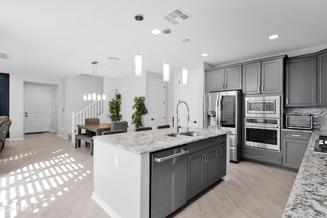 kitchen featuring light stone counters, visible vents, a sink, stainless steel appliances, and a chandelier