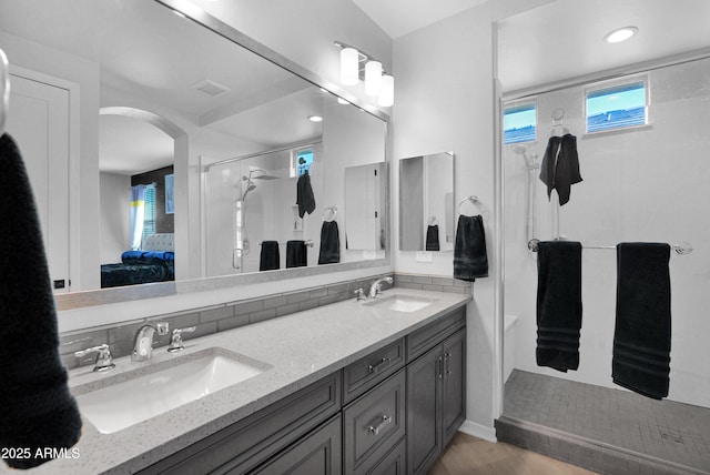 ensuite bathroom with double vanity, an enclosed shower, connected bathroom, and a sink