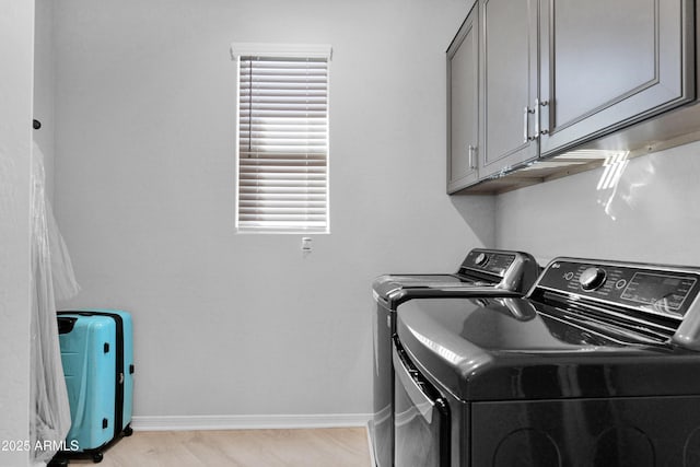 laundry area with light wood finished floors, cabinet space, baseboards, and separate washer and dryer