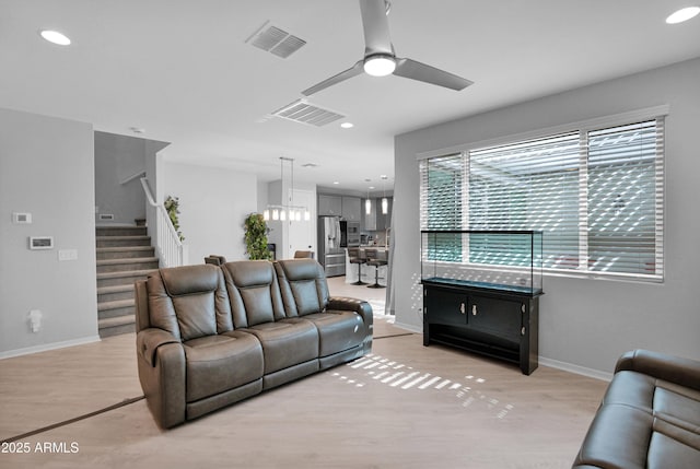 living area with visible vents, recessed lighting, light wood-type flooring, and stairs