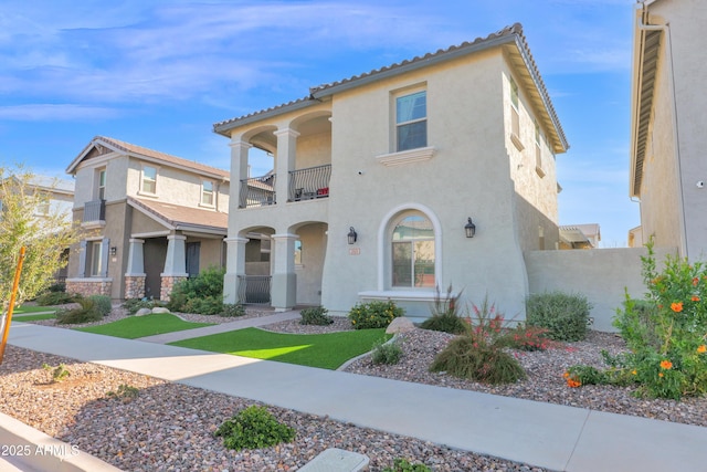 mediterranean / spanish-style home featuring stucco siding, a balcony, and a tiled roof