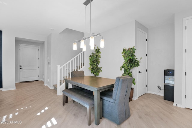 dining space featuring stairway, light wood-style flooring, and baseboards