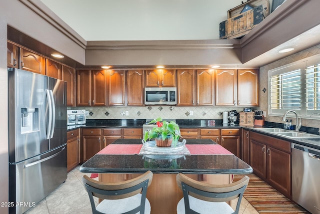 kitchen featuring decorative backsplash, stainless steel appliances, a kitchen island, and dark stone countertops