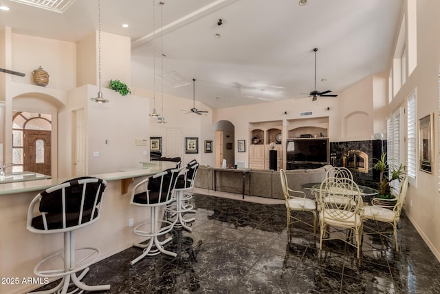 dining area with ceiling fan, a high end fireplace, and a high ceiling