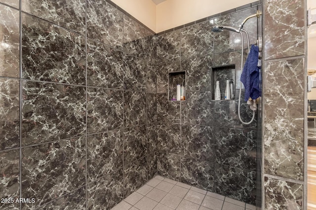 bathroom featuring a tile shower and tile patterned flooring