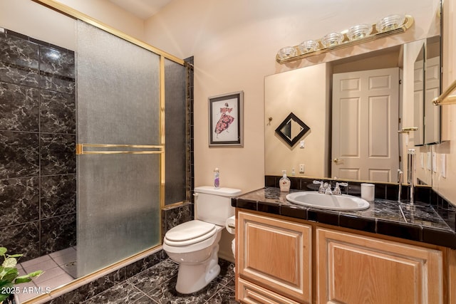 bathroom featuring toilet, a shower with door, and vanity