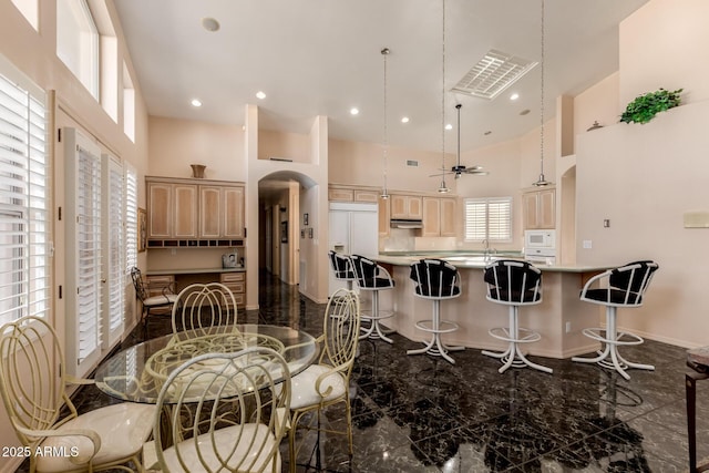 kitchen featuring built in appliances, light brown cabinets, a high ceiling, and ceiling fan