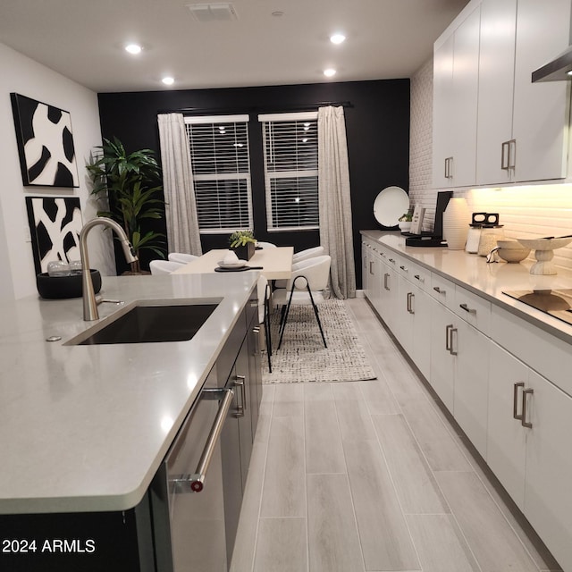 kitchen featuring white cabinetry, sink, stainless steel dishwasher, ventilation hood, and black electric stovetop