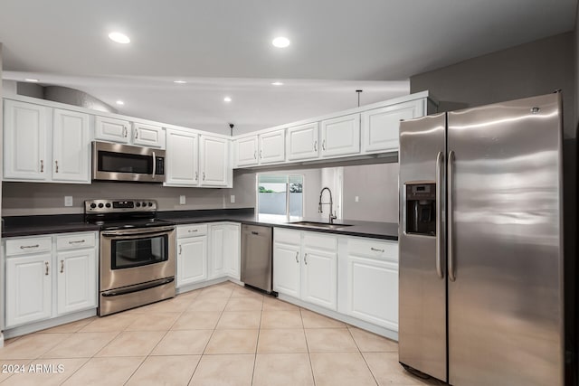 kitchen with white cabinetry, sink, lofted ceiling, light tile patterned floors, and appliances with stainless steel finishes