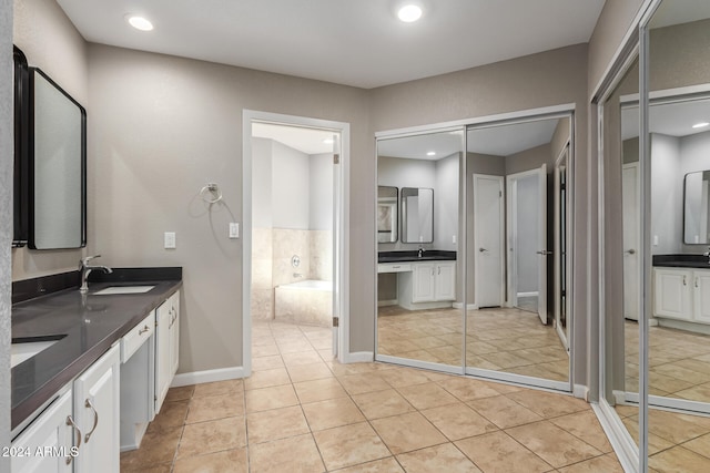 bathroom featuring tile patterned flooring, vanity, and tiled tub