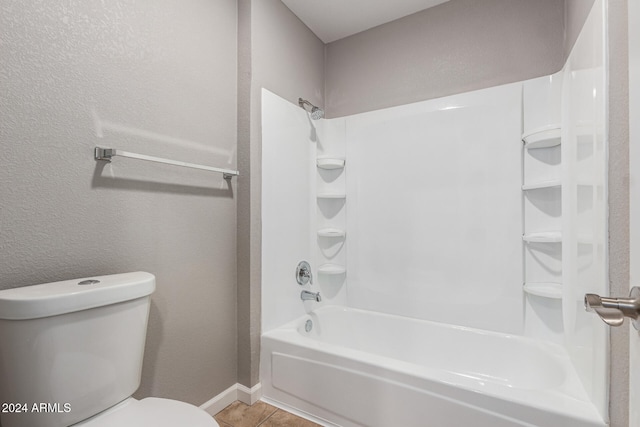 bathroom featuring tile patterned flooring, shower / bathing tub combination, and toilet