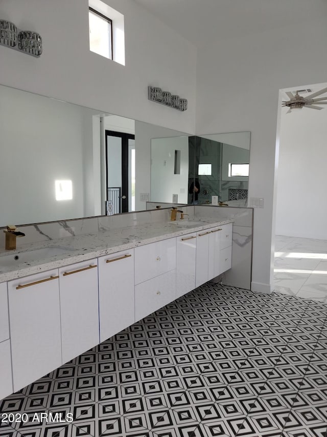 bathroom featuring ceiling fan, tile flooring, a washtub, and dual bowl vanity