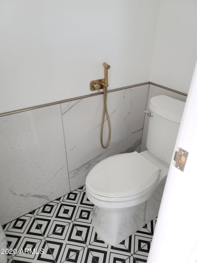 bathroom featuring tile flooring, toilet, and tile walls