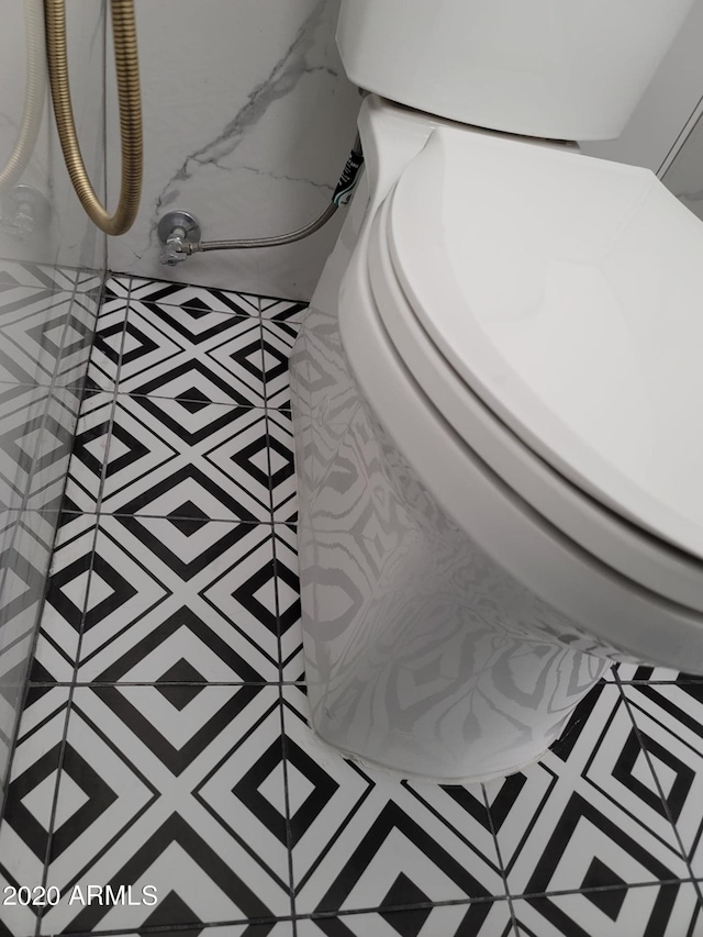 interior details with light tile flooring and toilet