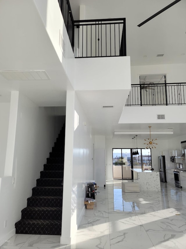 stairway featuring a notable chandelier and a towering ceiling