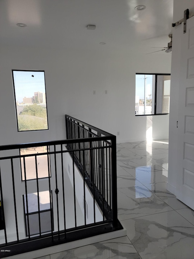 staircase featuring ceiling fan, tile floors, and a barn door