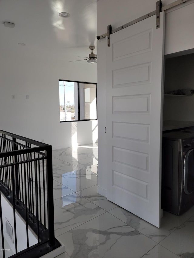 hall featuring a barn door, washer / clothes dryer, and light tile flooring