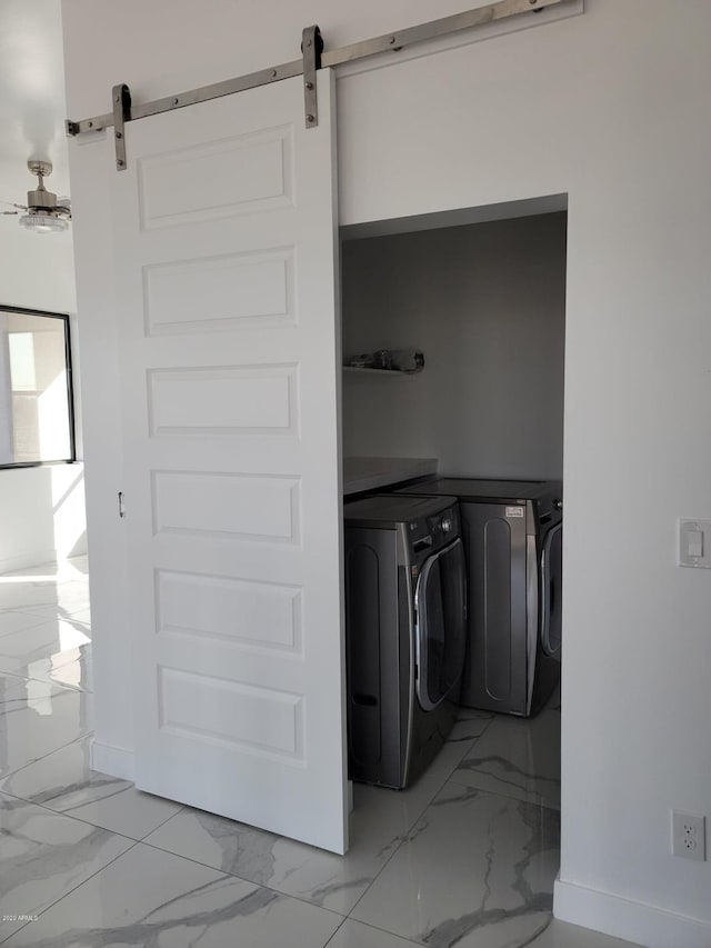 laundry room featuring light tile floors, washing machine and clothes dryer, and a barn door