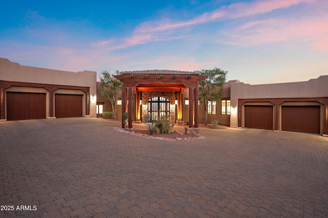 pueblo-style house featuring a garage, decorative driveway, and stucco siding