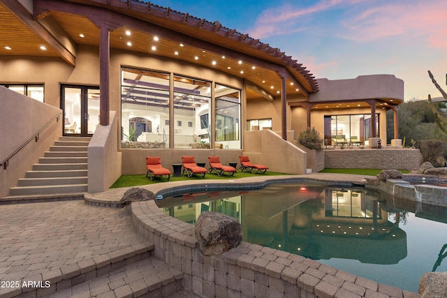 pool at dusk featuring a patio area, stairs, and an outdoor pool