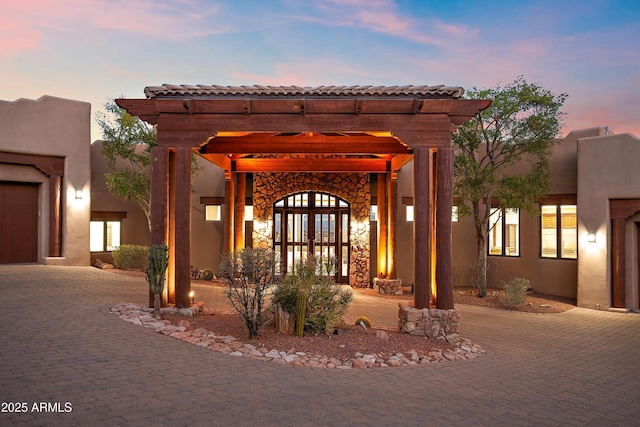 exterior space with a pergola, decorative driveway, and stucco siding